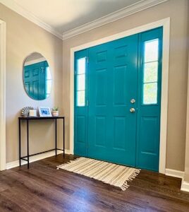 Bright blue front door, small entry table and mirror